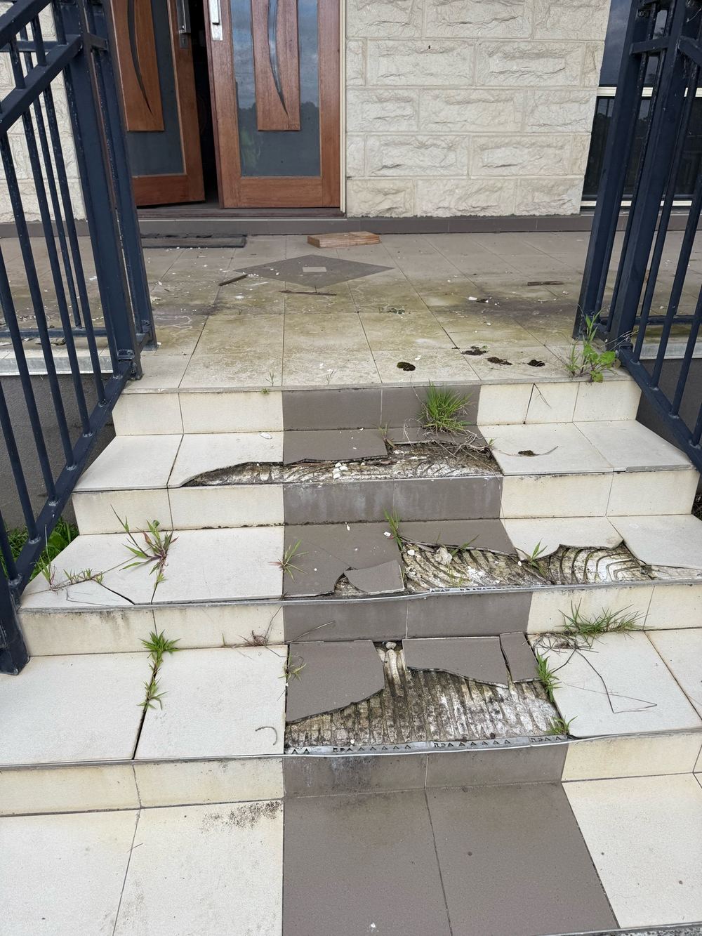 Balcony tiles lifting and delaminating from moisture trapped beneath them, found during a defect investigation inspection in Officer