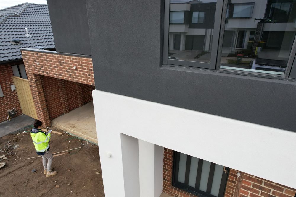 Rendered ledge at a cladding change with no flashing to shed water, found during a pre-handover inspection in Officer