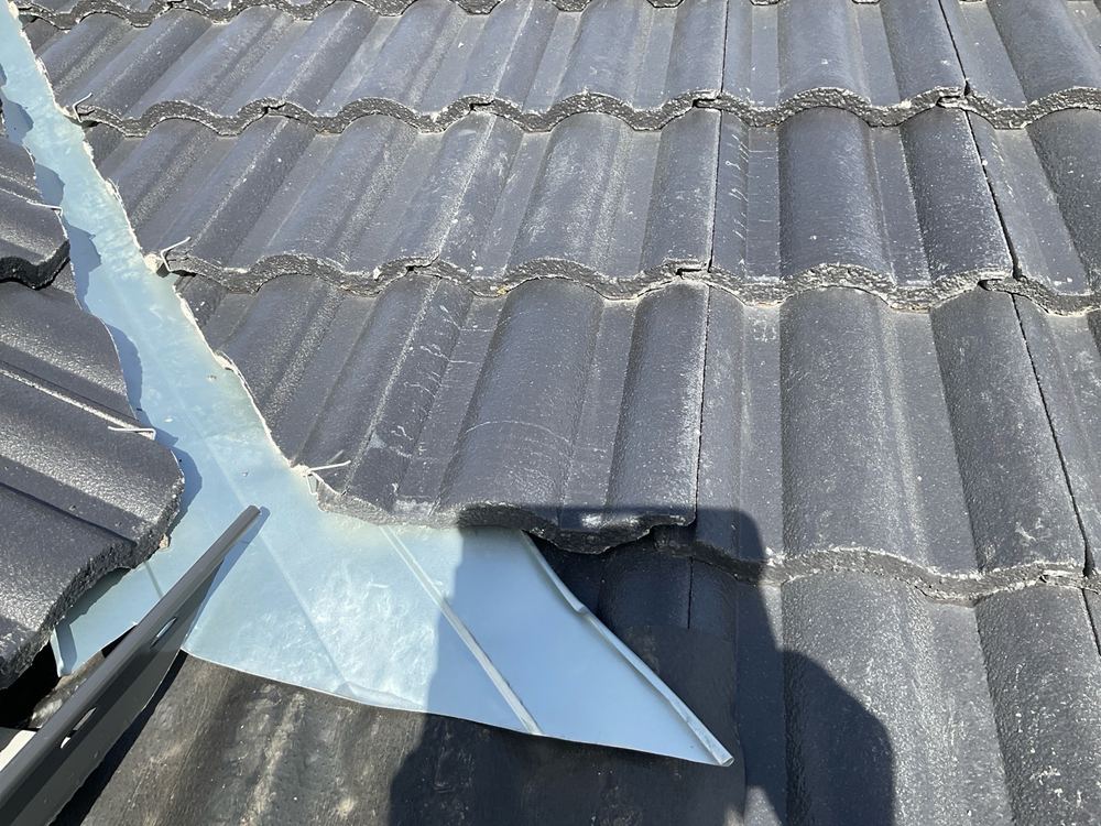 Broken roof tiles still in place at handover, risking leaks into the ceiling, found during a pre-handover inspection in Officer