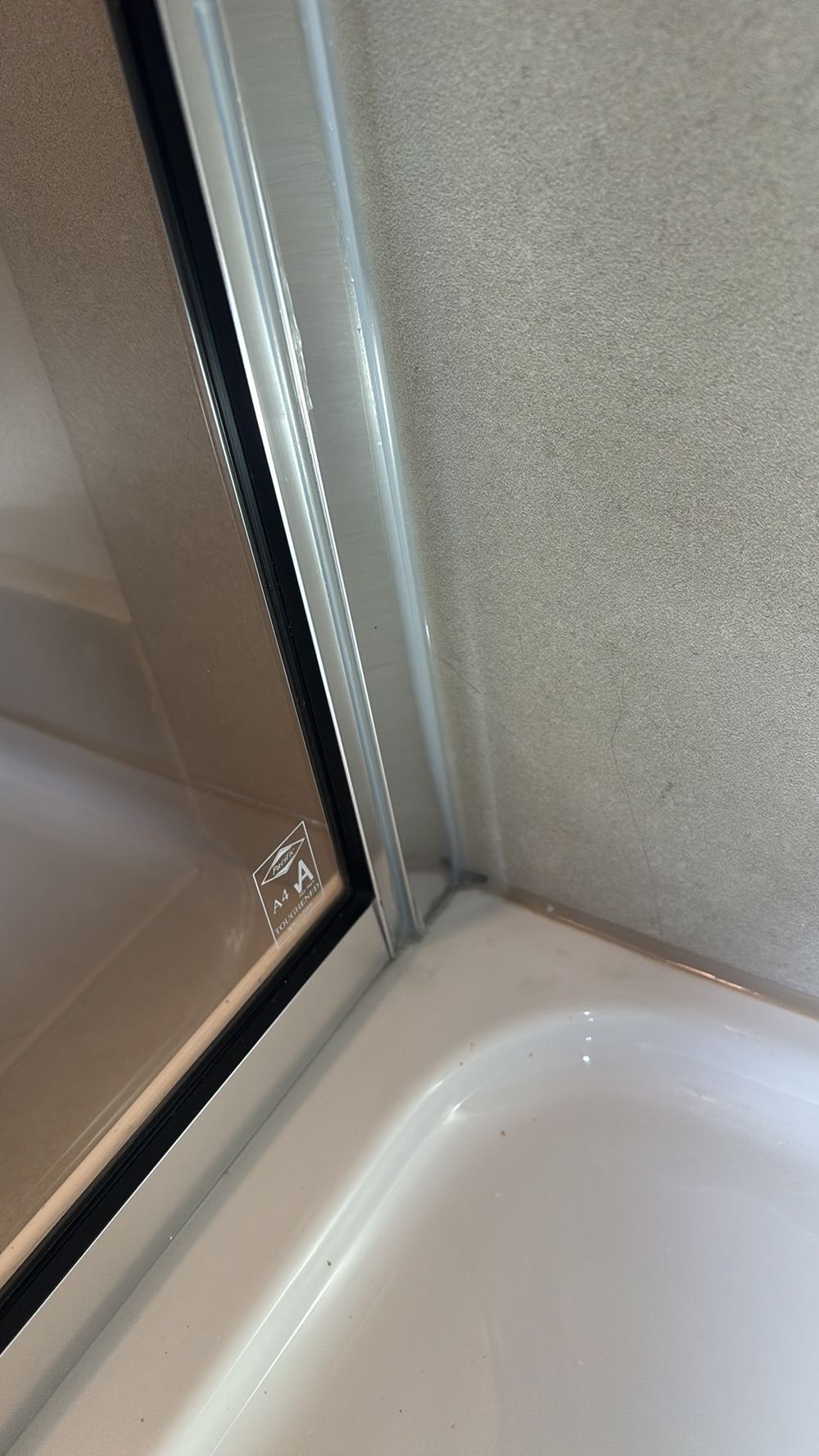 Shower screen channel sealed on the wet side, which can trap water behind it, found during a pre-handover inspection in Officer