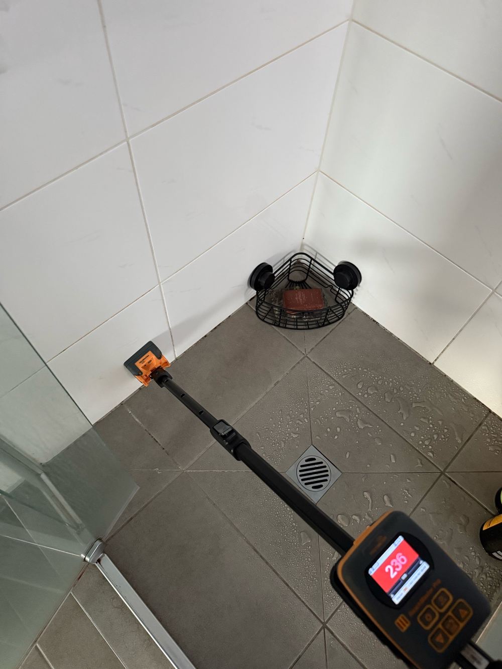 Moisture meter showing elevated readings at the base of a shower wall, found during a pre-purchase inspection in Officer